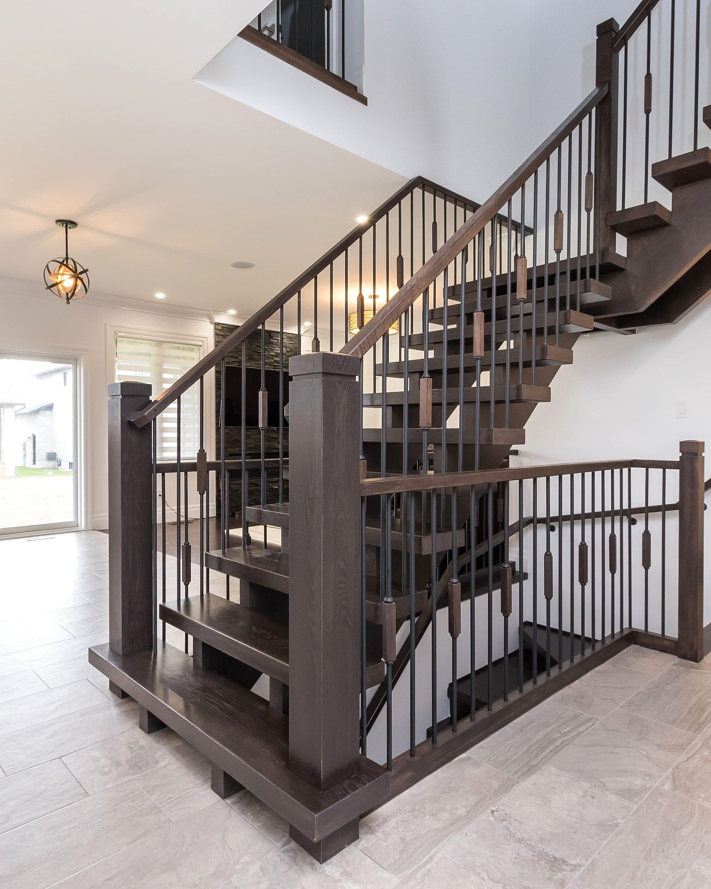 Custom stained-oak staircase with iron spindles in a completed Black Cedar home